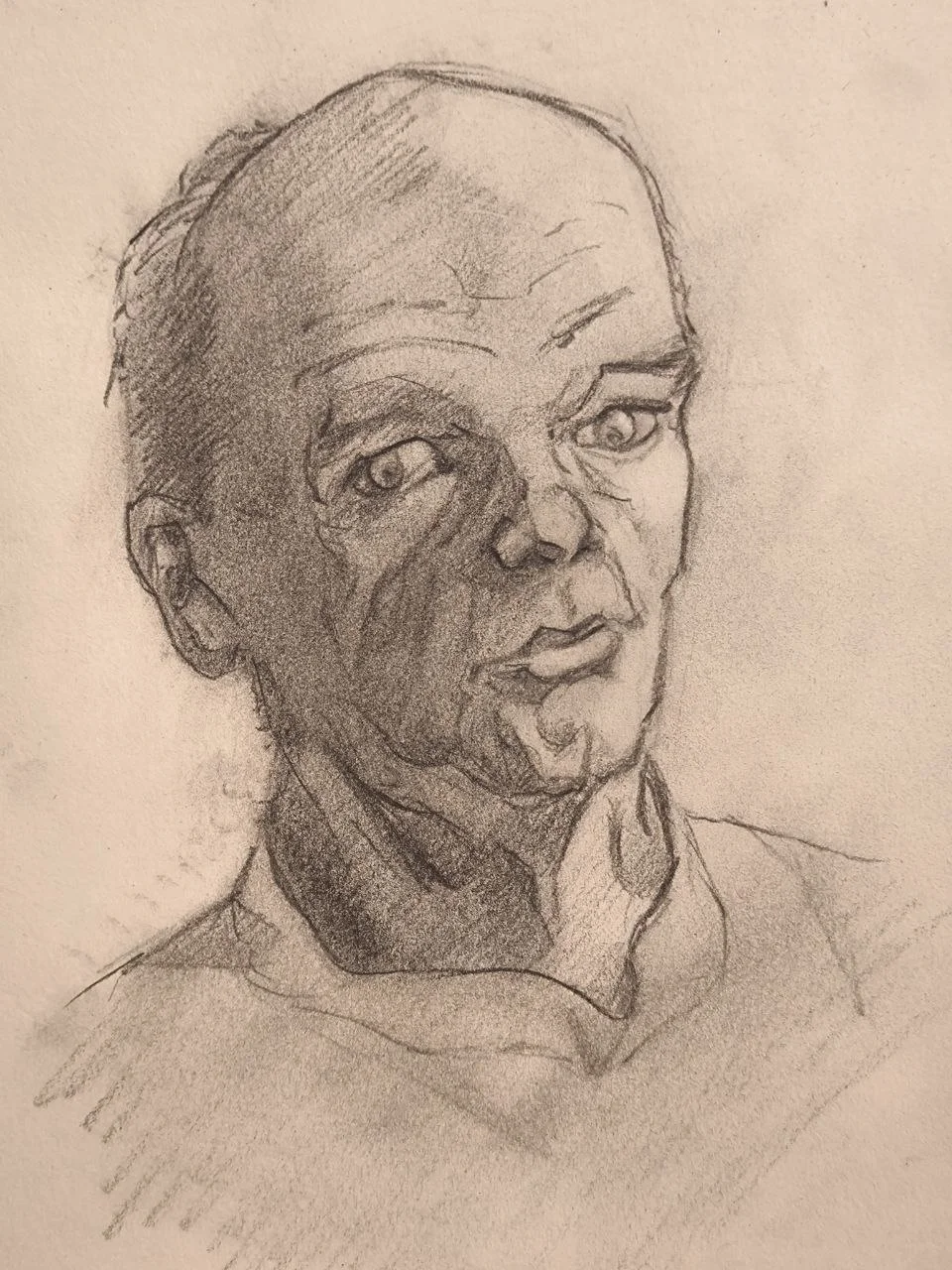 Graphite portrait sketch of a bald man in three-quarter view, looking slightly to the side, with strong shadow shapes across the face and loose, expressive shading on a plain background.