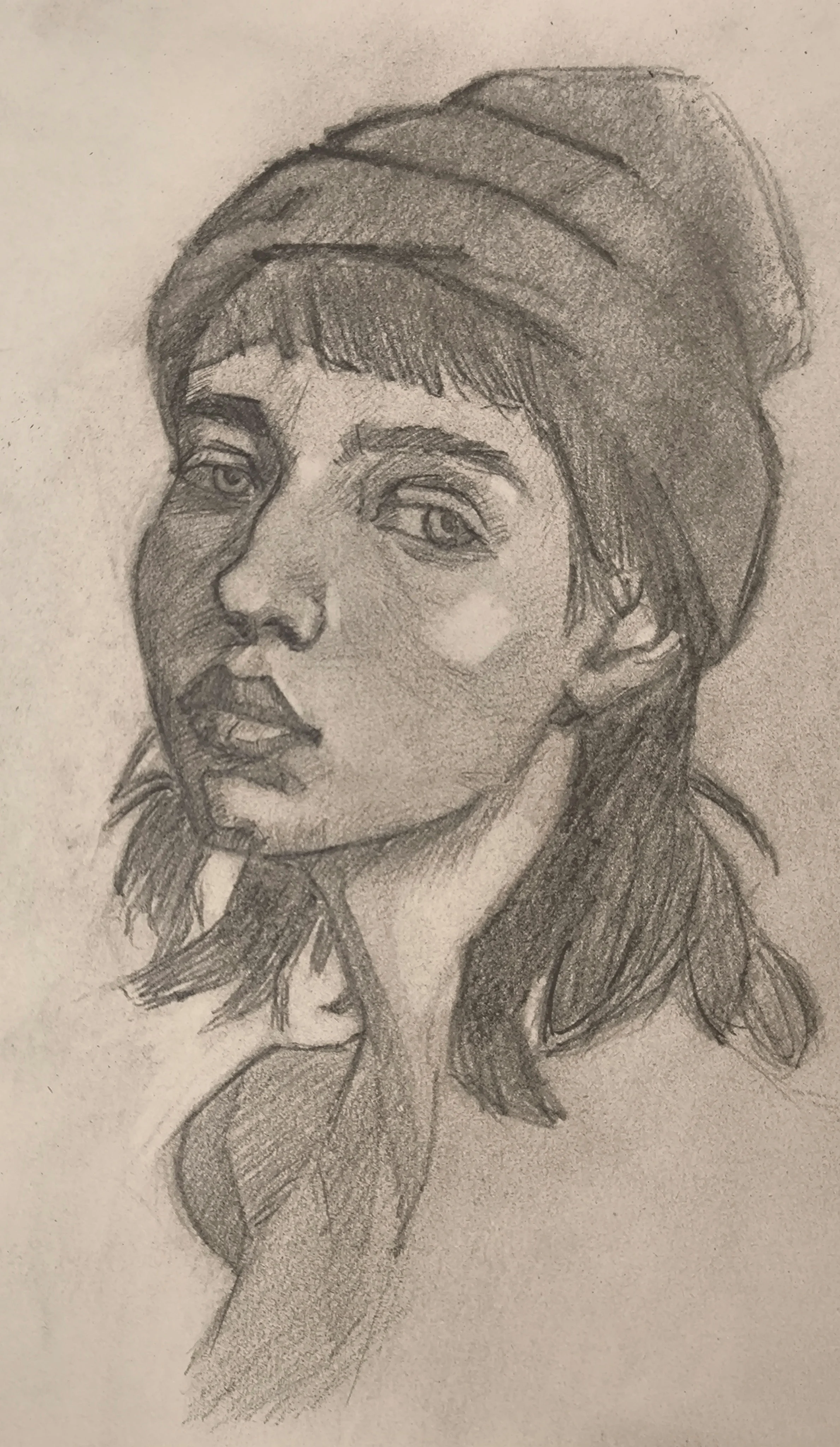 Graphite portrait sketch of a woman in a beanie, three-quarter view with her head slightly tilted up, eyes looking off to the side, and soft shading defining the nose, lips, and cheek.
