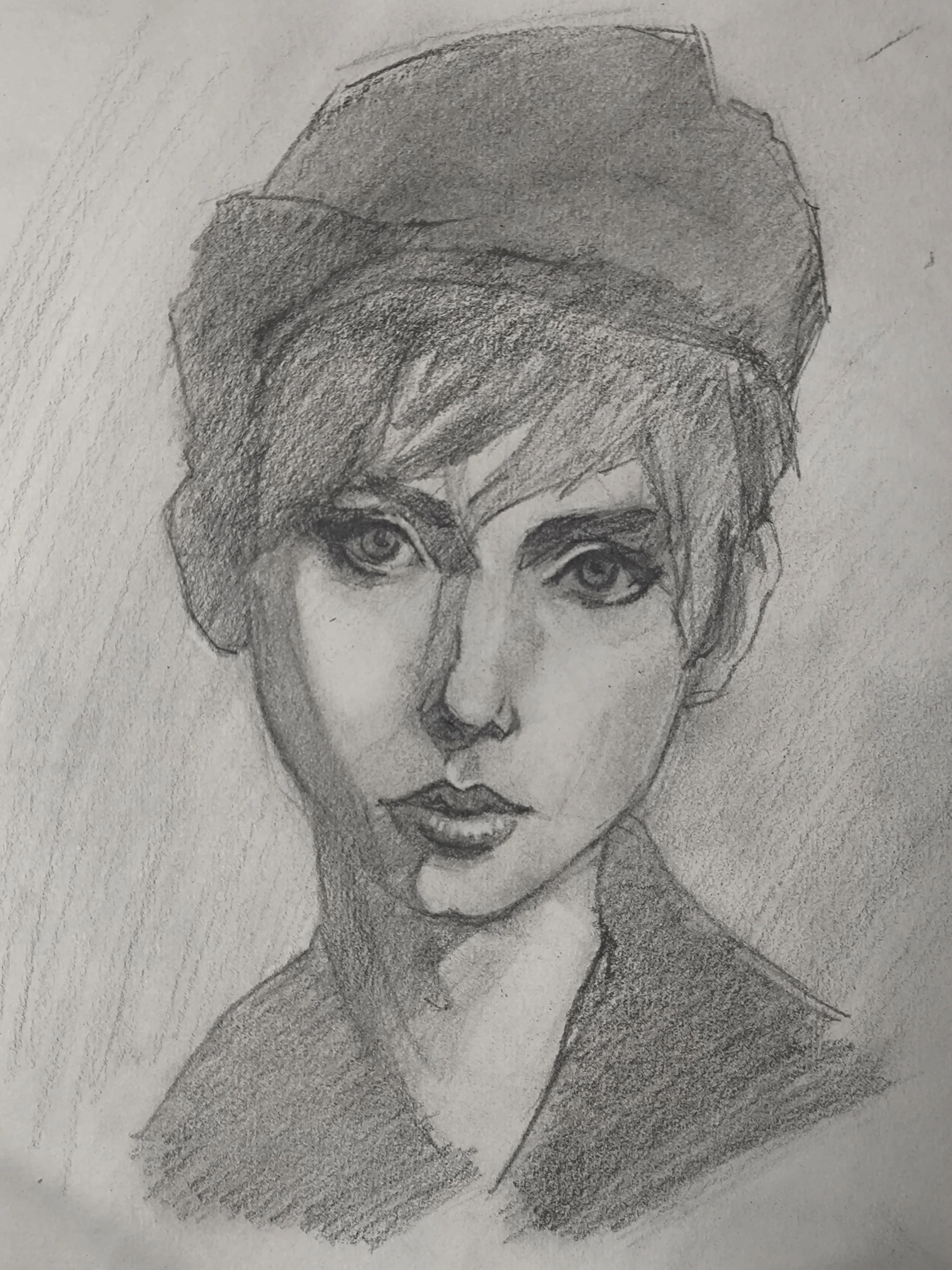 Graphite portrait sketch of a young woman facing forward, wearing a soft beret-like hat. Short hair falls over one eye, with big focused eyes and dark shading around the nose and lips. Strong light and shadow split the face, and a simple jacket collar is suggested.