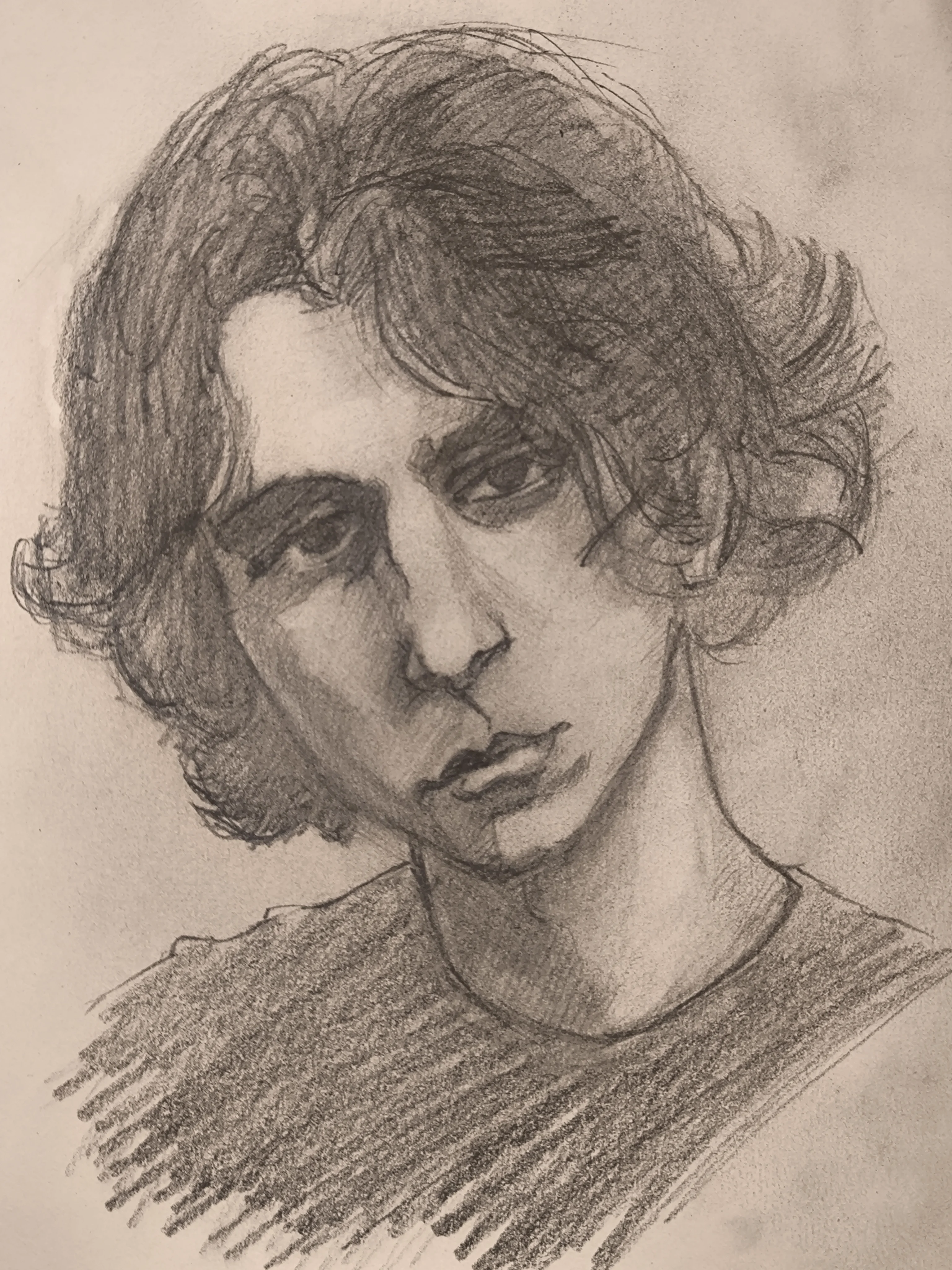 A graphite portrait sketch of a young man with wavy medium length hair. The head is slightly tilted, with a calm but tired expression and heavy shadow around the eyes and nose. Loose pencil lines shape the curls, and the shirt is filled with quick diagonal strokes.
