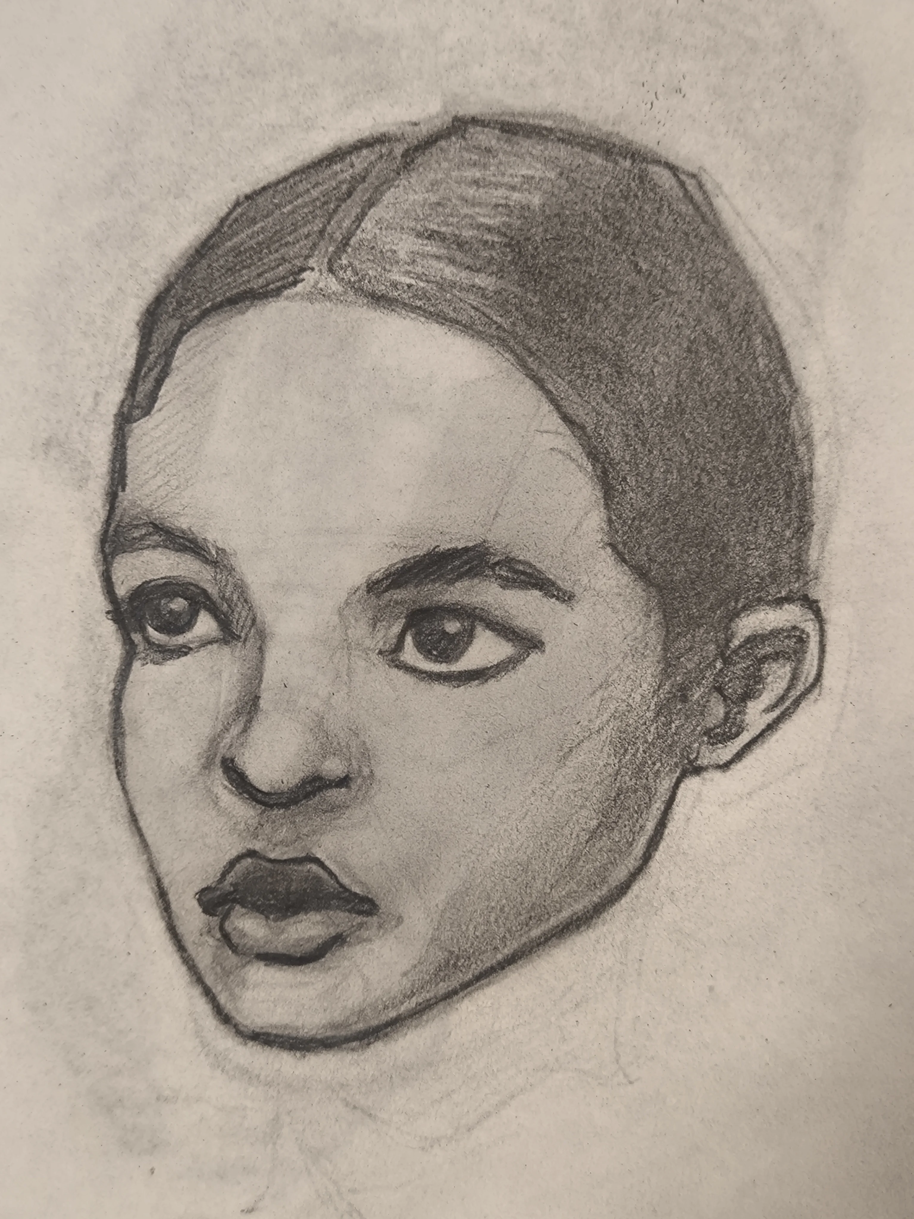 Graphite sketch of a woman’s head in 3/4 view. Hair is pulled back with a middle part, big eyes looking forward, and dark shaded lips. Soft shading on the cheek and jaw.