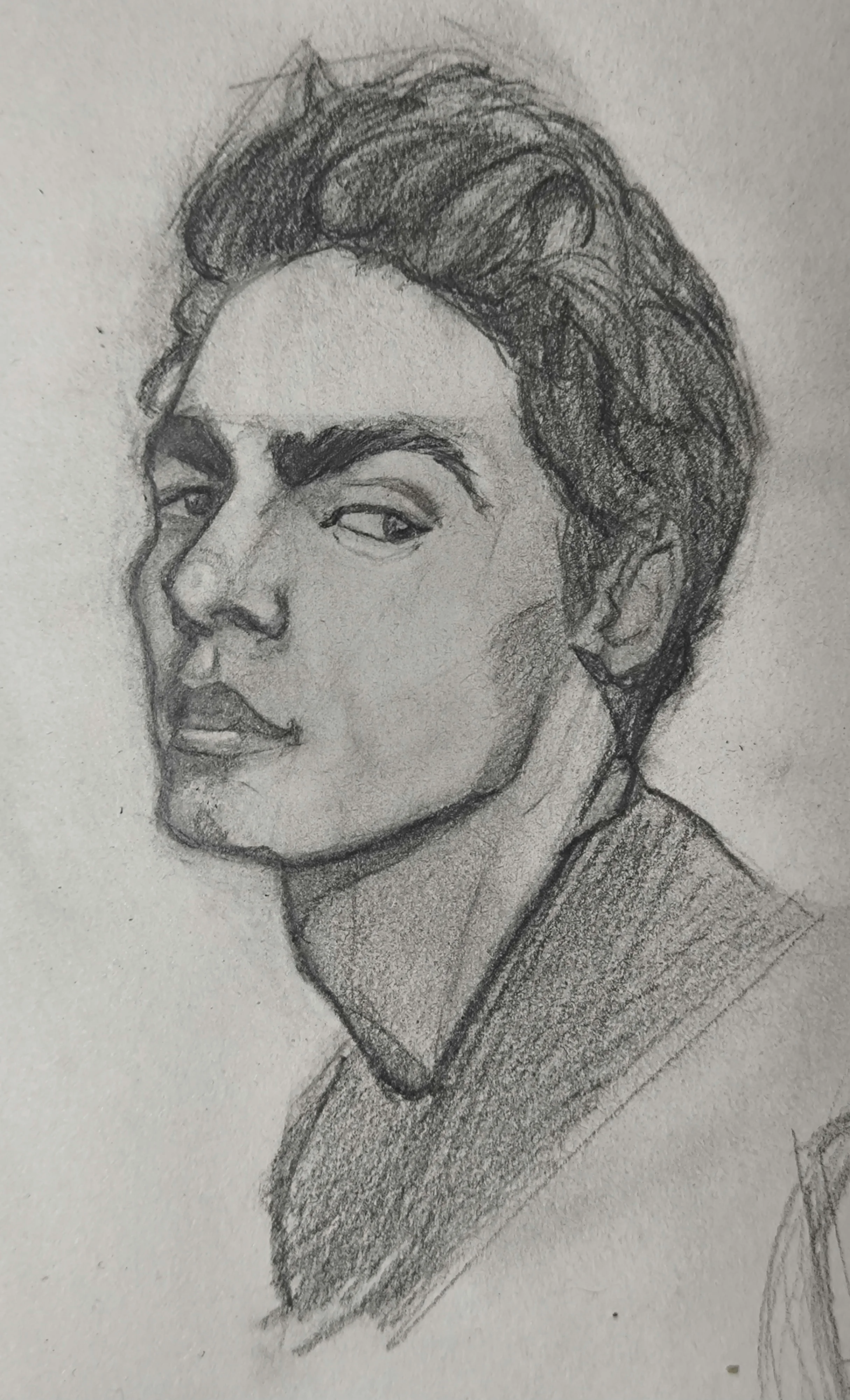 Graphite pencil portrait sketch of a young man in three quarter view, looking sideways with a sharp eyebrow and calm expression. Dark shaded hair swept back, strong jawline, and a shaded shirt.